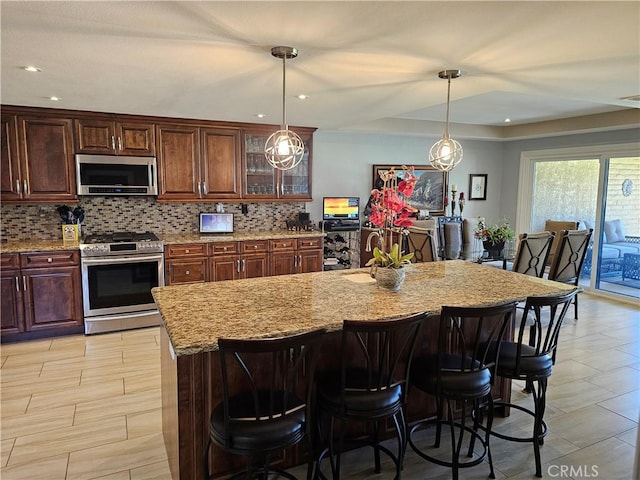 kitchen featuring appliances with stainless steel finishes, a kitchen island with sink, and backsplash