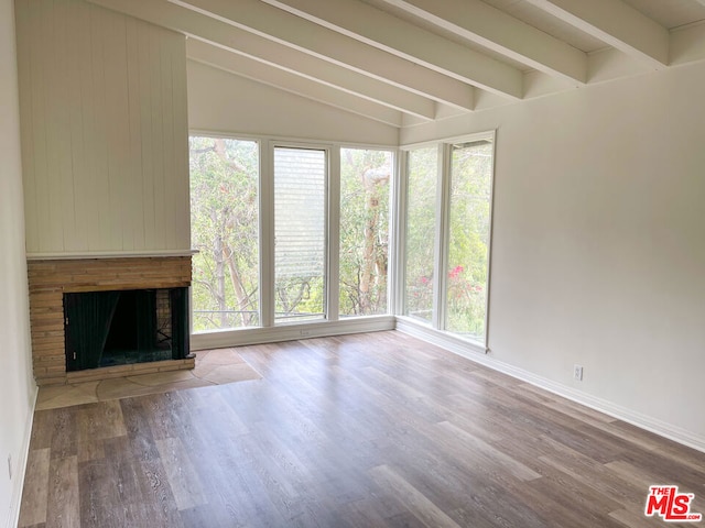 unfurnished living room with hardwood / wood-style flooring, plenty of natural light, and vaulted ceiling with beams