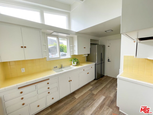 kitchen featuring white cabinetry, sink, tile counters, and stainless steel refrigerator