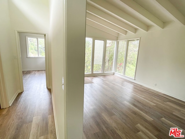 unfurnished room featuring vaulted ceiling with beams and hardwood / wood-style flooring