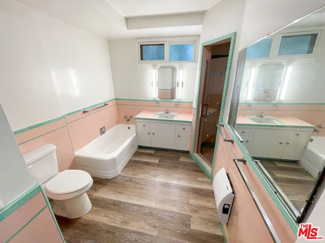 full bathroom with toilet, wood-type flooring, tile walls, vanity, and plus walk in shower