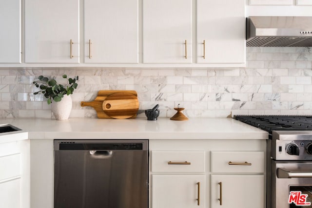 kitchen with wall chimney range hood, decorative backsplash, white cabinets, and appliances with stainless steel finishes