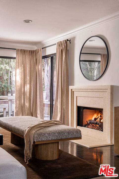 bedroom featuring a premium fireplace, dark wood-type flooring, and crown molding