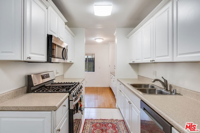 kitchen featuring white cabinetry, stainless steel appliances, light tile patterned flooring, and sink