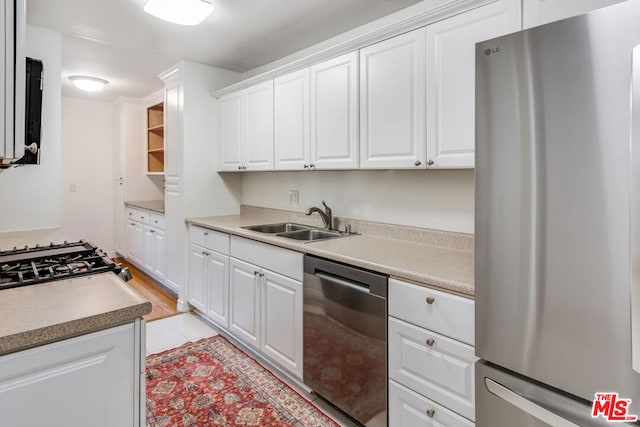 kitchen featuring light tile patterned floors, stainless steel appliances, sink, and white cabinets