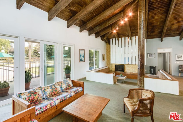 interior space with beam ceiling, a brick fireplace, high vaulted ceiling, and wood ceiling