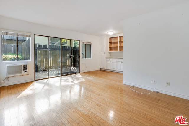 unfurnished room with a wall mounted AC and light wood-type flooring