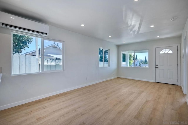 foyer entrance with a wall mounted AC and light wood-type flooring