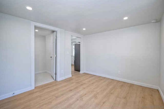 unfurnished bedroom featuring light hardwood / wood-style flooring and stainless steel refrigerator