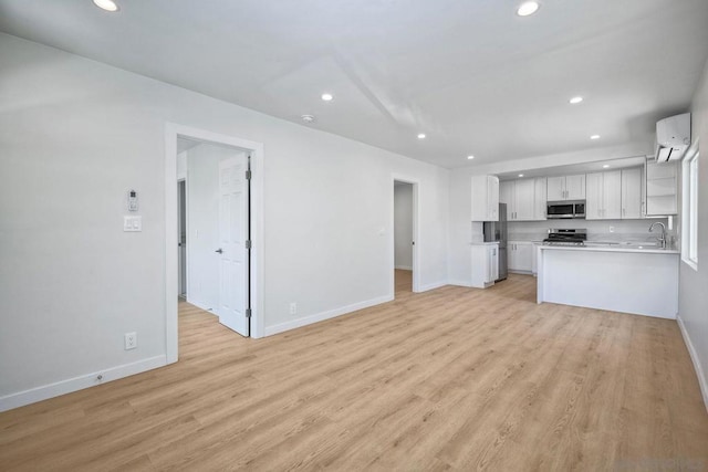 kitchen with stainless steel appliances, white cabinets, light hardwood / wood-style floors, and kitchen peninsula