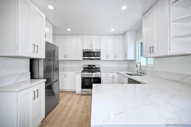 kitchen with white cabinetry, stainless steel appliances, sink, and light stone counters