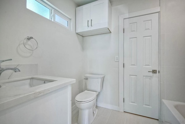 bathroom featuring a tub to relax in, vanity, and toilet