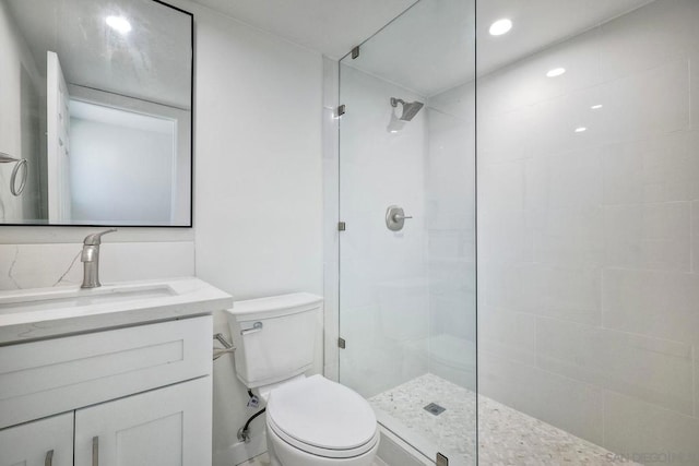 bathroom featuring vanity, toilet, and a tile shower