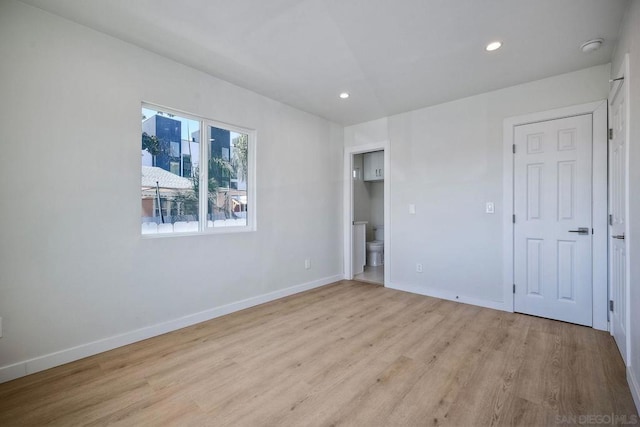 unfurnished bedroom featuring ensuite bath and light wood-type flooring