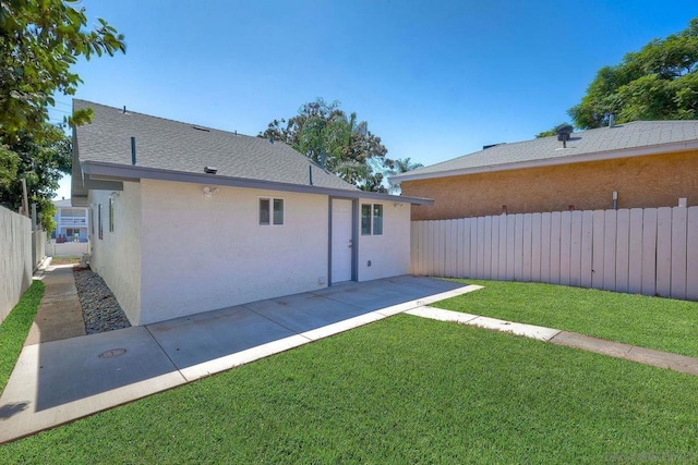 back of property with a yard and a patio area