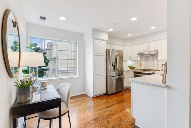 kitchen featuring white cabinetry, tasteful backsplash, stainless steel appliances, and light stone counters