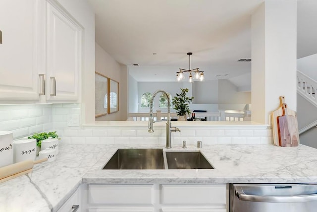 kitchen with sink, kitchen peninsula, dishwasher, light stone countertops, and white cabinets