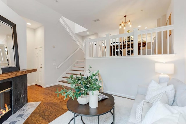 living room featuring a tiled fireplace, hardwood / wood-style flooring, and an inviting chandelier