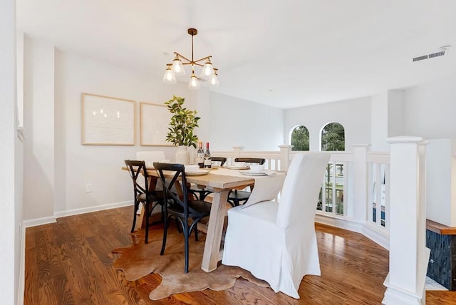 dining room with dark wood-type flooring and a chandelier