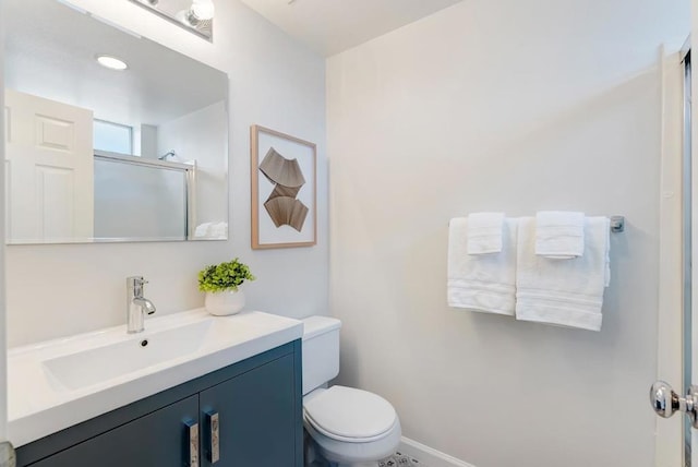 bathroom with vanity, a shower with shower door, and toilet