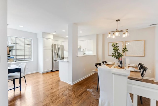 dining room featuring sink, a notable chandelier, and light hardwood / wood-style flooring