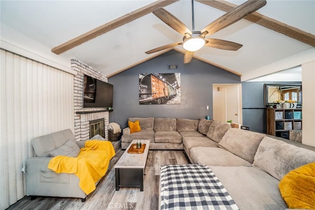 living room featuring lofted ceiling with beams, ceiling fan, a fireplace, and light hardwood / wood-style flooring