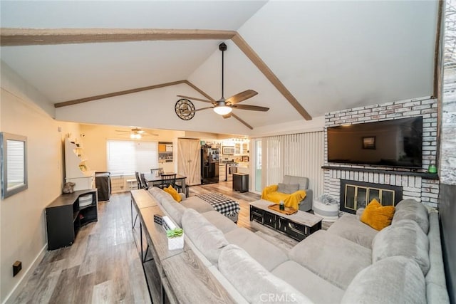 living room featuring ceiling fan, wood-type flooring, high vaulted ceiling, and a brick fireplace