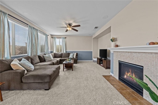 carpeted living room featuring ceiling fan and a tiled fireplace