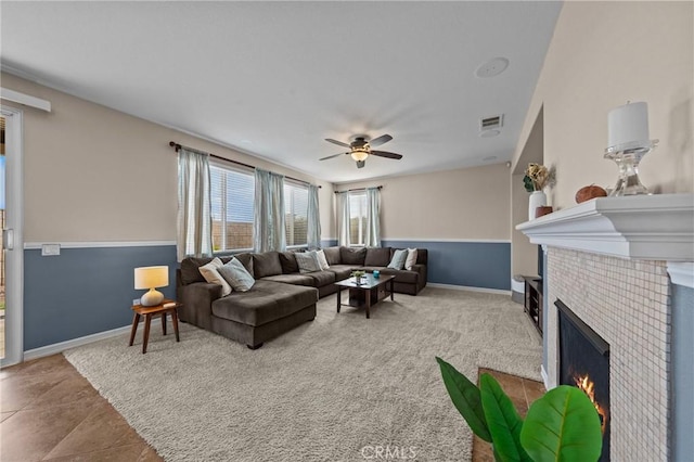 living room with a tile fireplace and ceiling fan