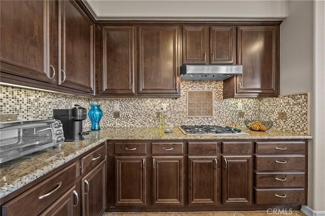 kitchen with dark brown cabinetry, light stone countertops, and stainless steel gas cooktop