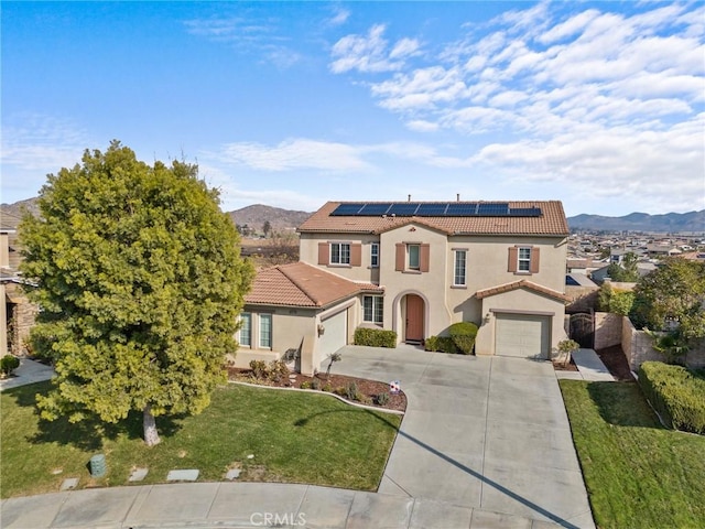 mediterranean / spanish-style home featuring a garage, a mountain view, a front lawn, and solar panels