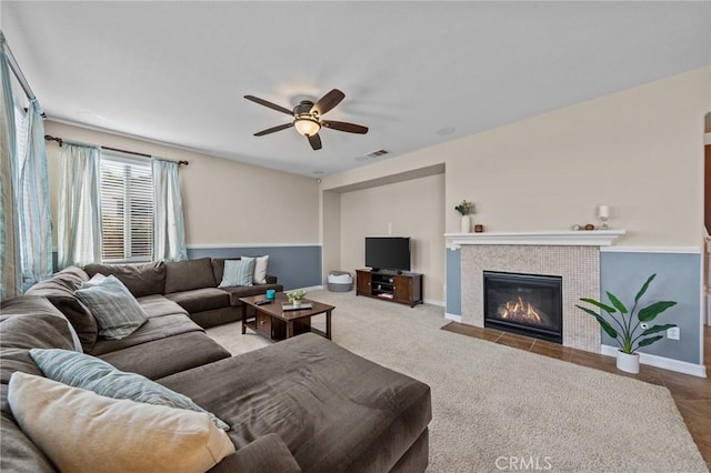 carpeted living room featuring a tile fireplace and ceiling fan