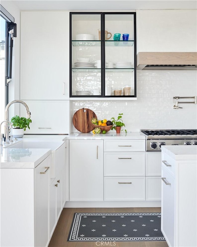 kitchen with tasteful backsplash, stainless steel gas stovetop, dark wood-type flooring, and white cabinets