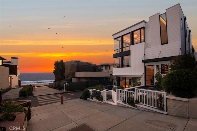 patio terrace at dusk featuring a water view