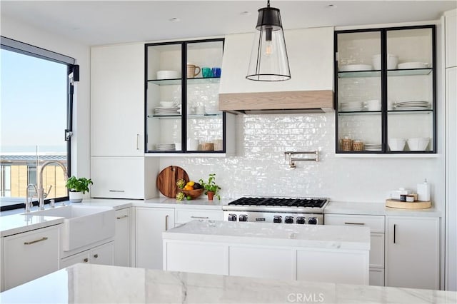 kitchen with sink, range, light stone countertops, white cabinets, and decorative light fixtures