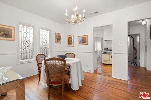 dining space with light hardwood / wood-style floors and a notable chandelier