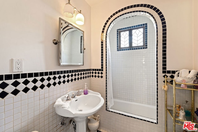 bathroom with tile walls, sink, and tiled shower / bath