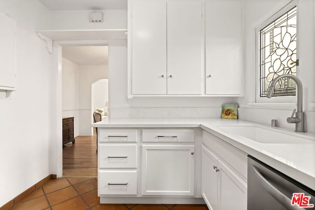 kitchen featuring dark tile patterned floors, white cabinetry, sink, and stainless steel dishwasher