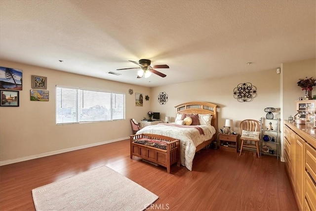 bedroom featuring a textured ceiling, wood finished floors, ceiling fan, and visible vents