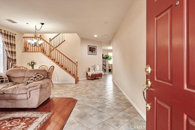 foyer entrance with stairway, visible vents, a notable chandelier, and baseboards