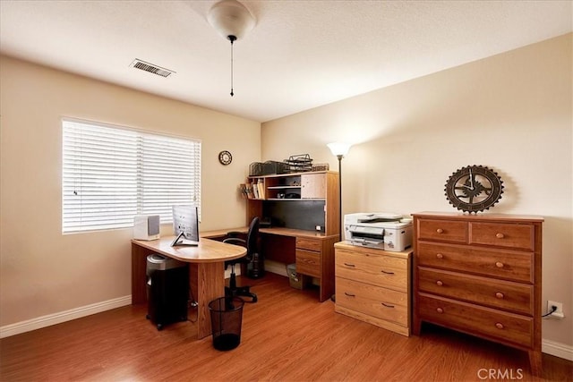 office space with light wood finished floors, visible vents, and baseboards