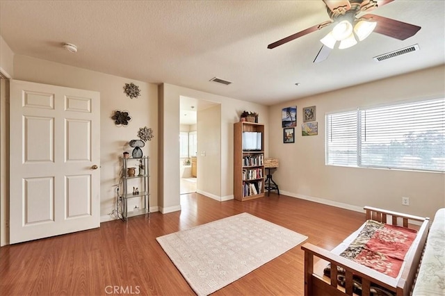 sitting room featuring wood finished floors, visible vents, a ceiling fan, and baseboards