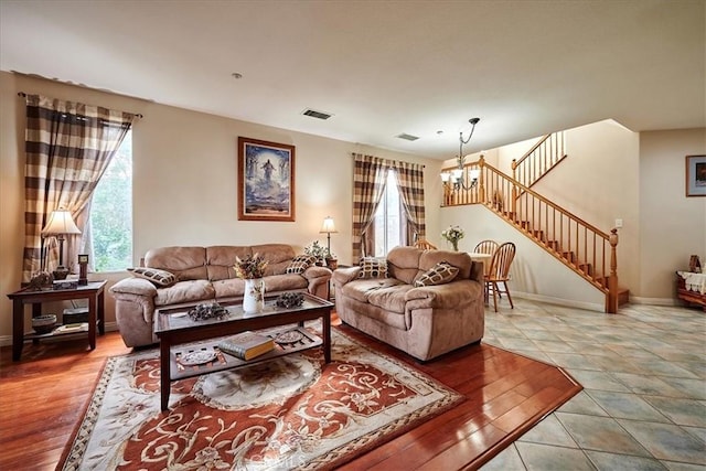 tiled living area featuring stairs, visible vents, a chandelier, and a healthy amount of sunlight