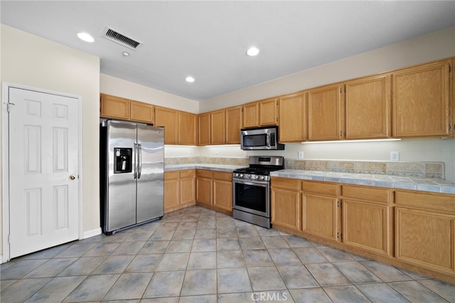 8015 Ralston Pl, Riverside, CA 92508 - kitchen with stainless steel appliances, tile counters, recessed lighting, and light tile patterned flooring