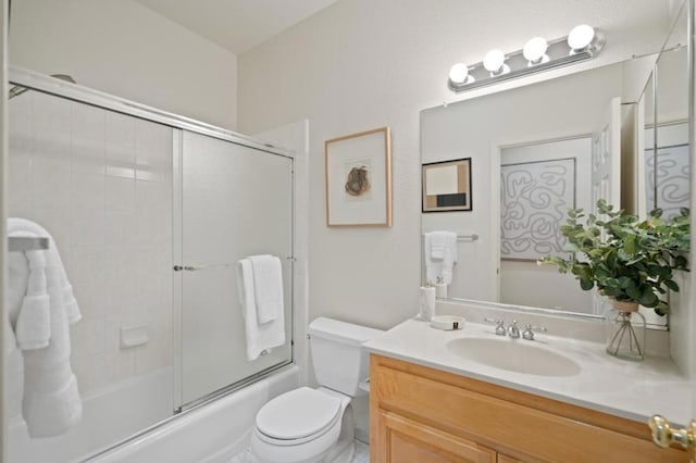 full bathroom featuring vanity, shower / bath combination with glass door, and toilet