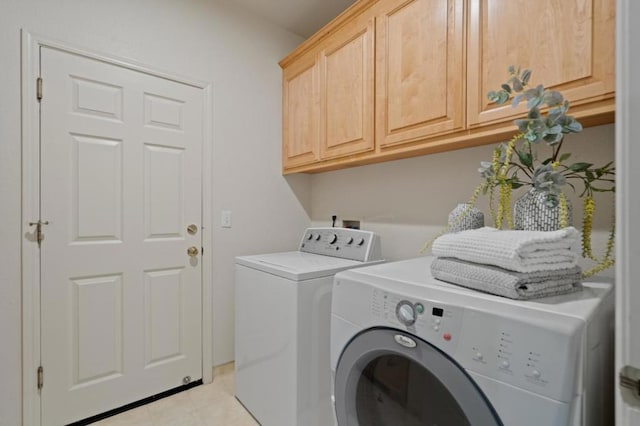 clothes washing area with cabinets and washer and dryer