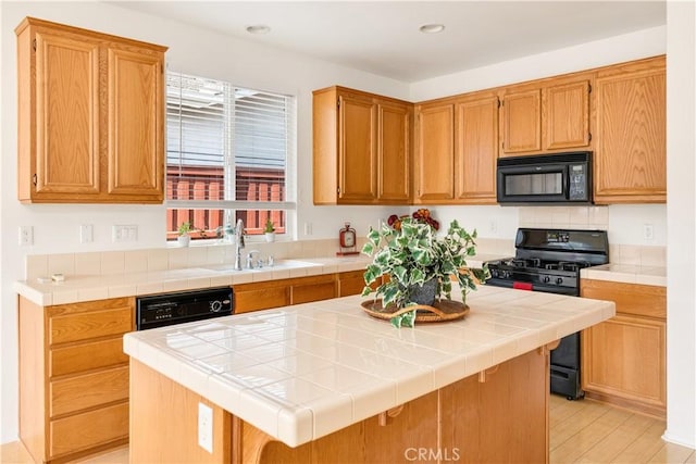 kitchen with tile counters, a center island, and black appliances