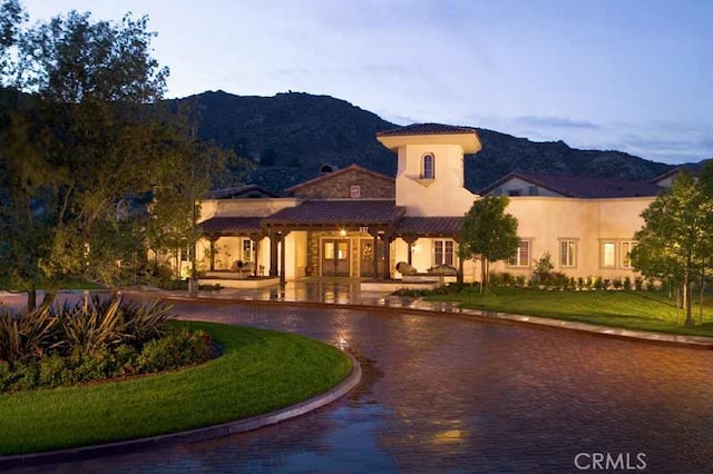 mediterranean / spanish-style house with a mountain view and a lawn