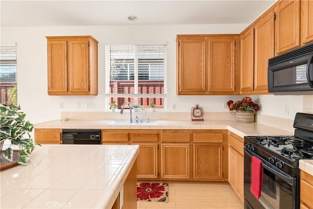 kitchen with sink, tile countertops, and black appliances