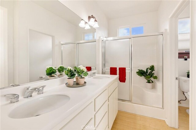 bathroom featuring hardwood / wood-style floors, vanity, toilet, a chandelier, and walk in shower